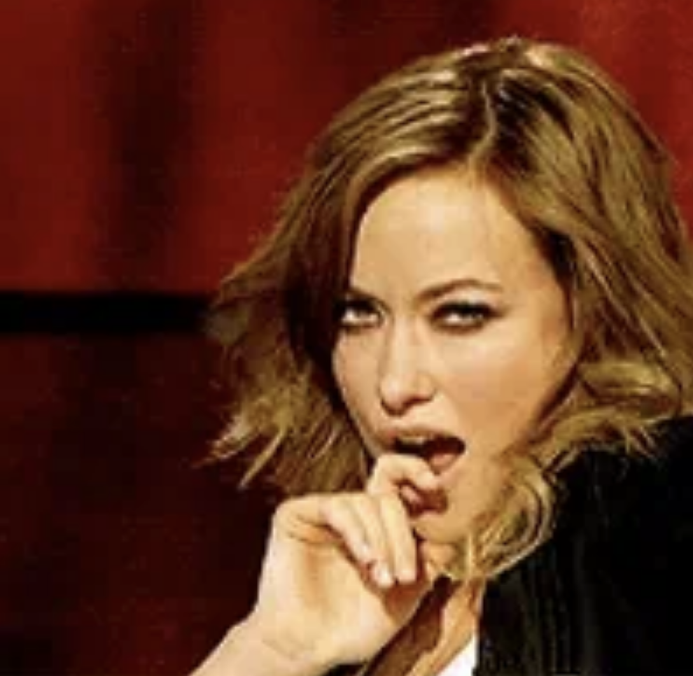 Olivia Wilde giving a sultry look while playfully biting her finger in a scene from a media event or show