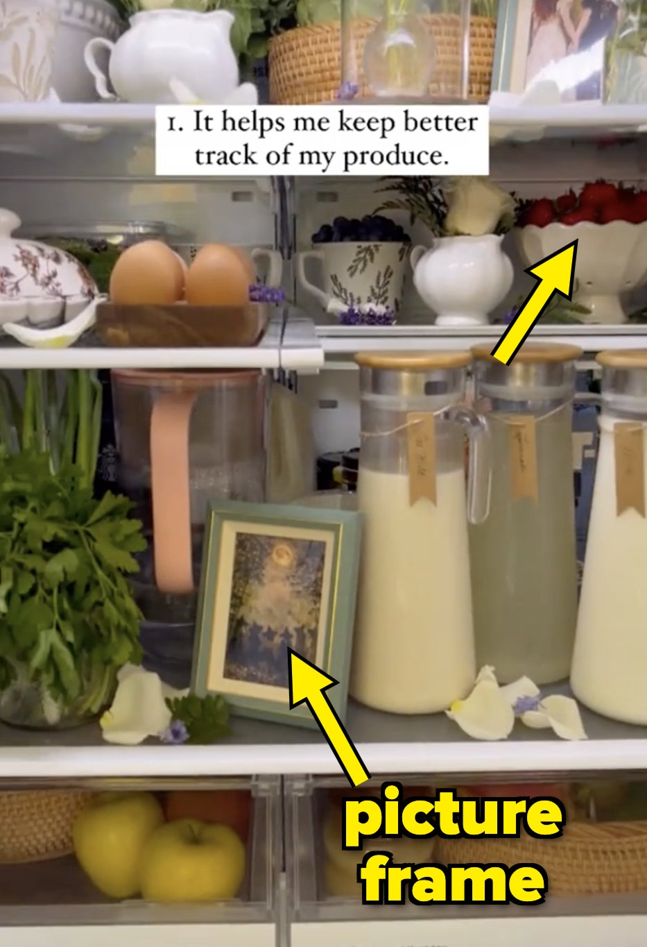 A neatly organized refrigerator with labeled containers, fruits, and vegetables. A comment reads, "It helps me keep better track of my produce." There is also a picture frame