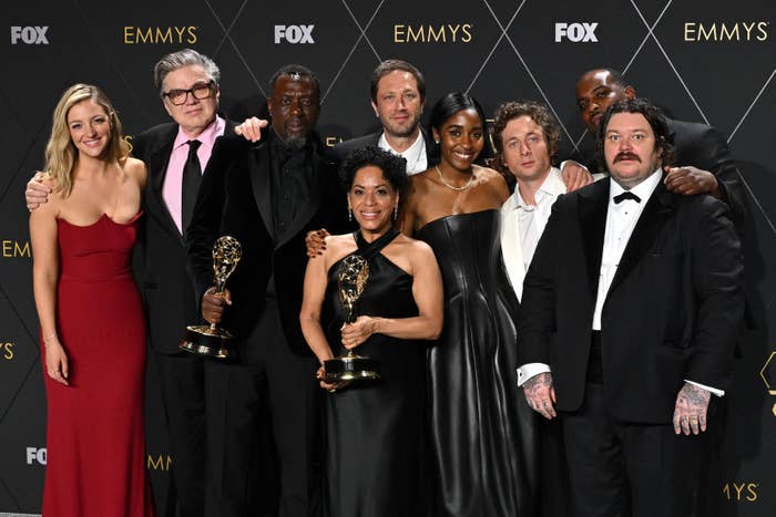 A group photo of the cast of &quot;The Bear&quot; standing on a red carpet with Emmy Awards