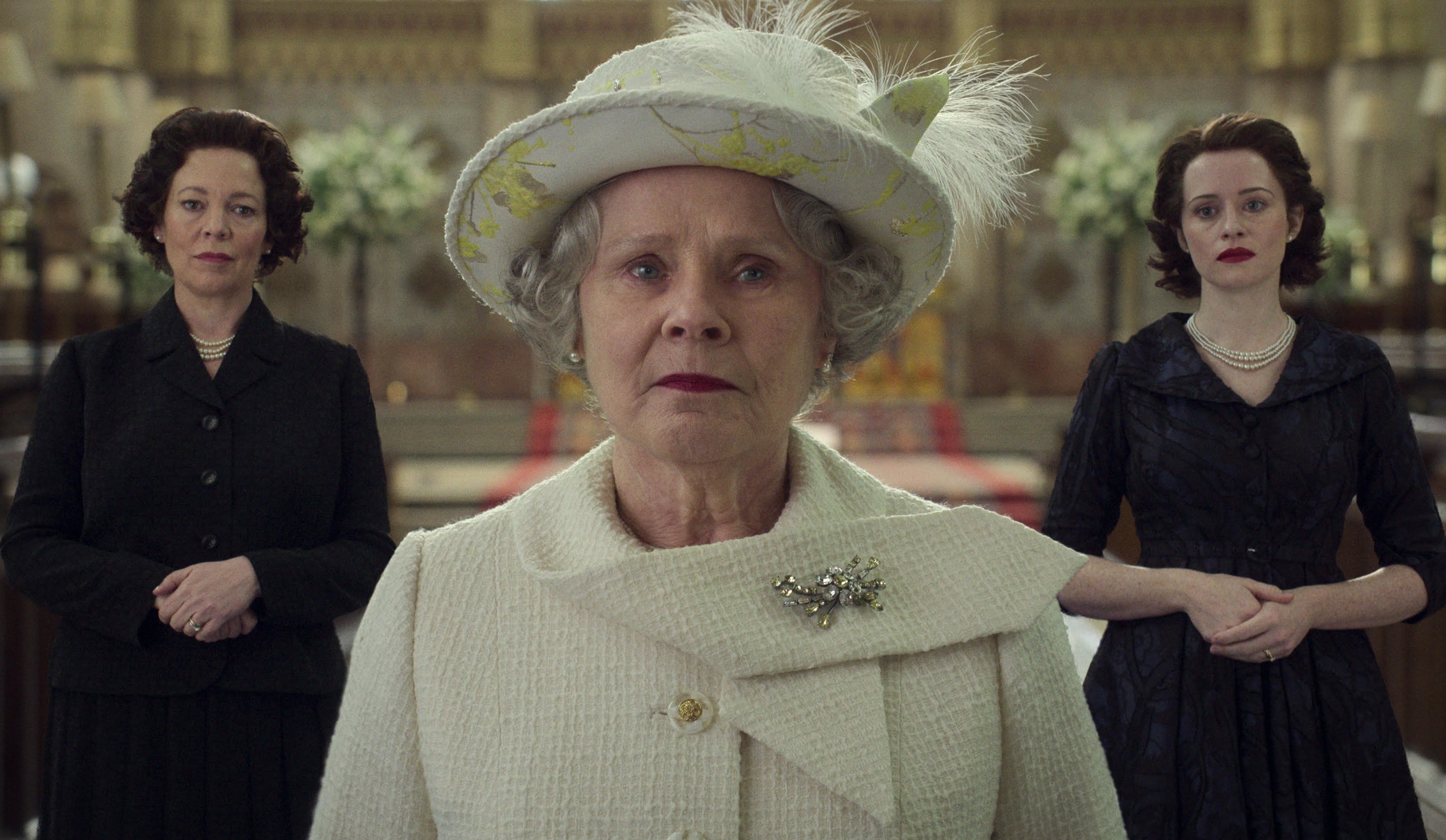 Olivia Colman, Imelda Staunton, and Claire Foy in period attire standing in a regal hallway, portrayed in scenes from &quot;The Crown&quot;