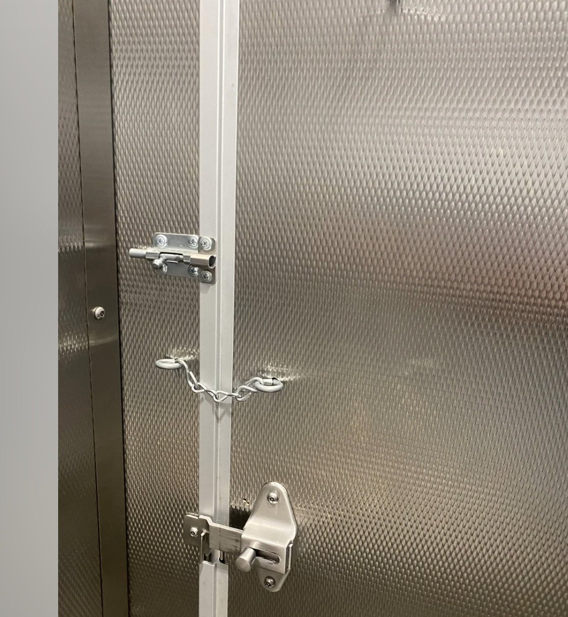 A metal door secured with a bolt lock, chain latch, and padlock