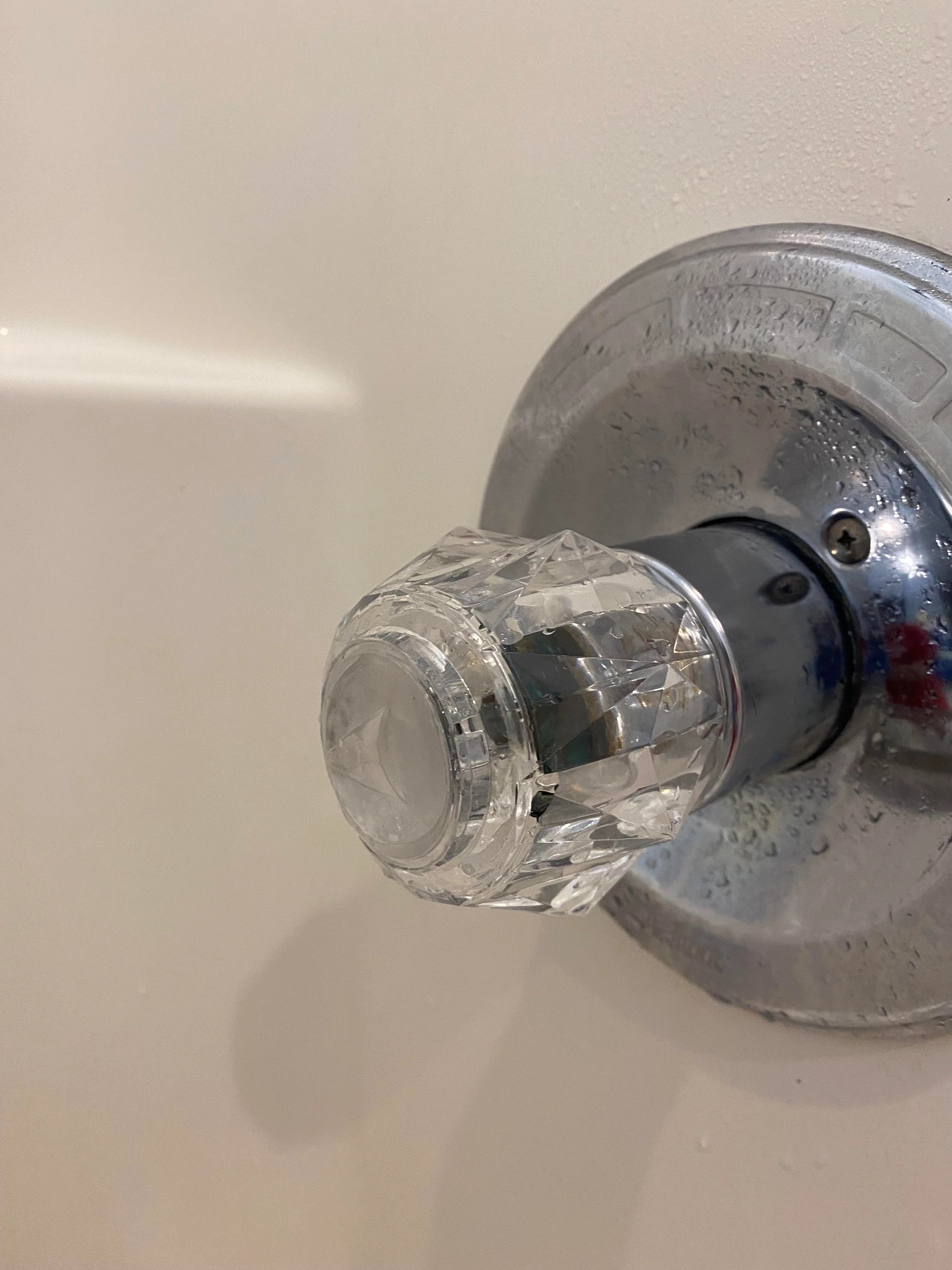 A close-up of a clear, crystal-like shower handle in a bathroom