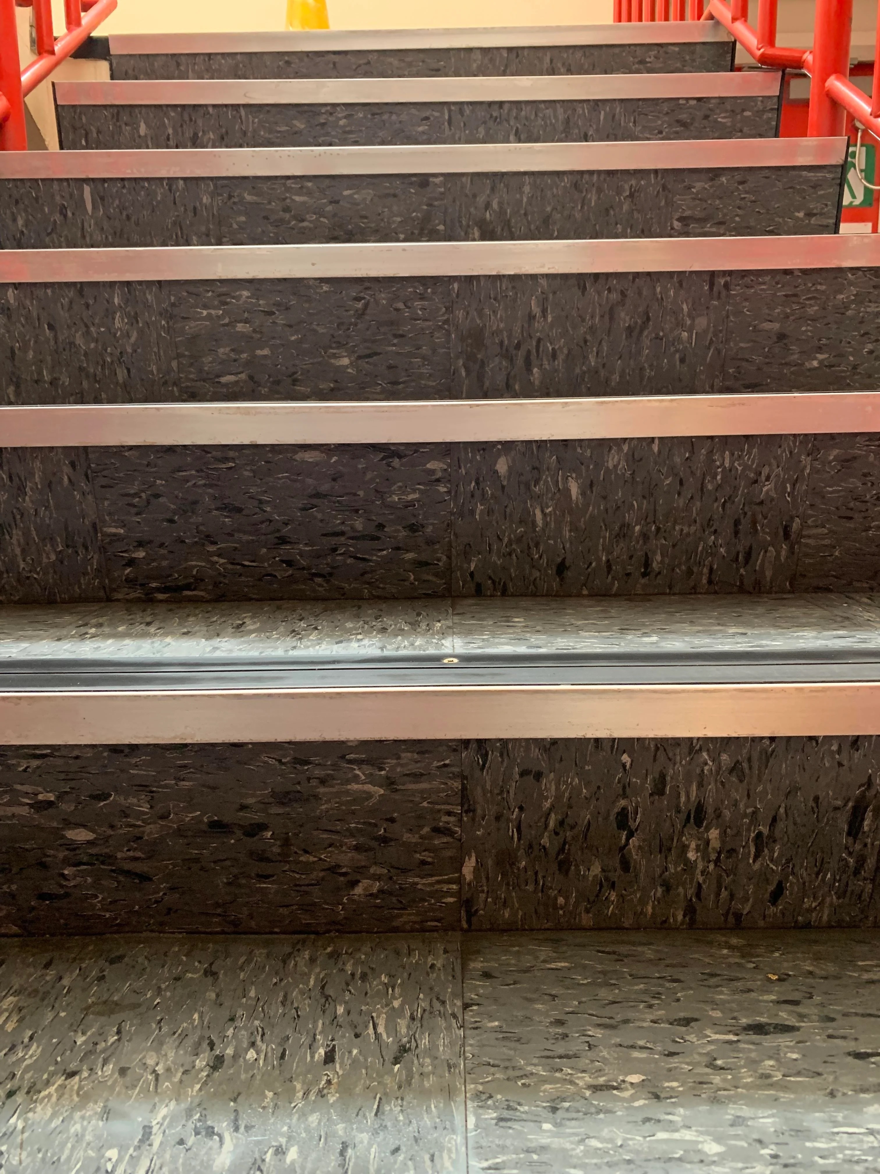A set of non-slip stairs with red railings visible on each side. No people are present