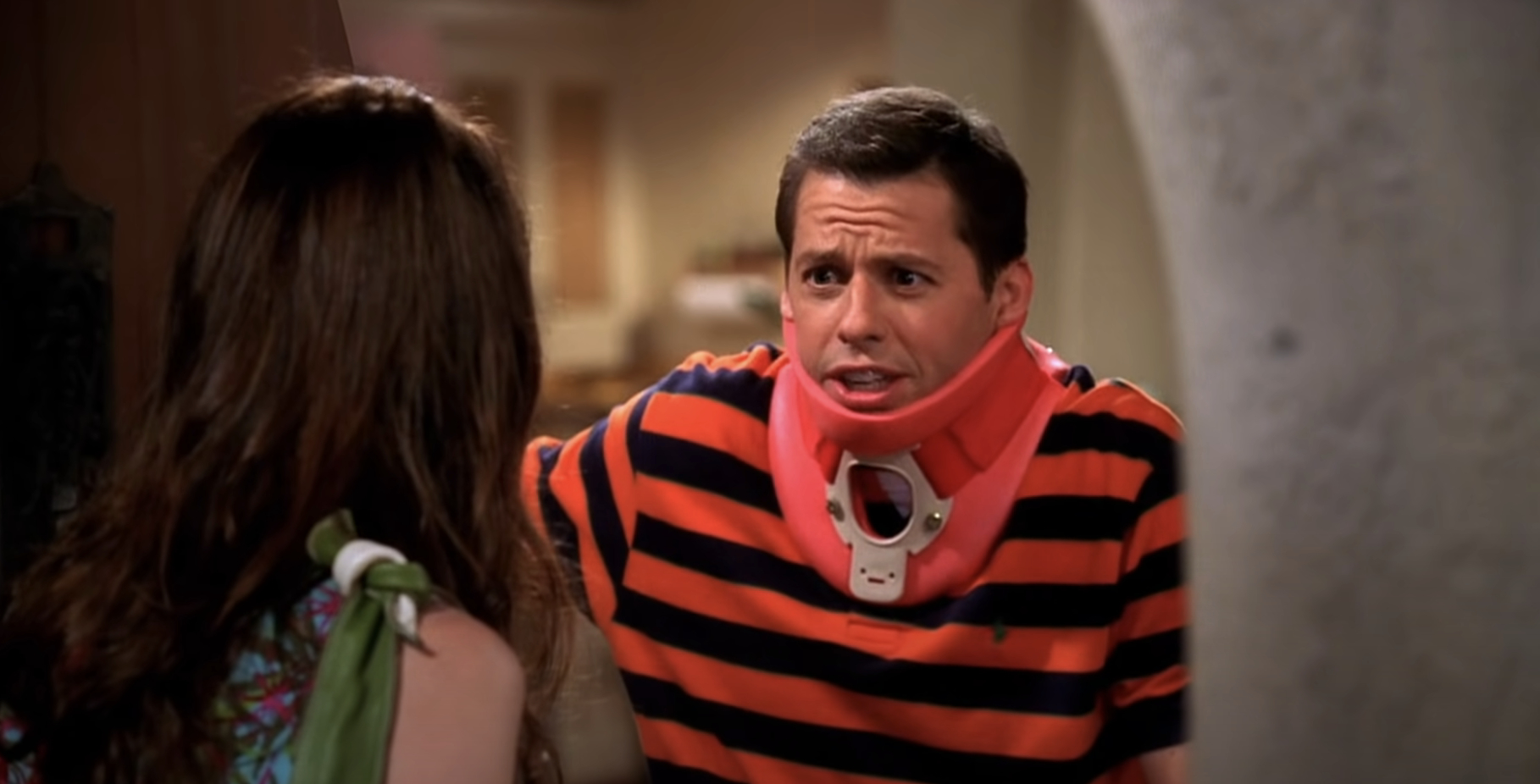 Jon Cryer in a striped shirt looks distressed, wearing a neck brace, talking to a woman with long hair on the show &quot;Two and a Half Men.&quot;