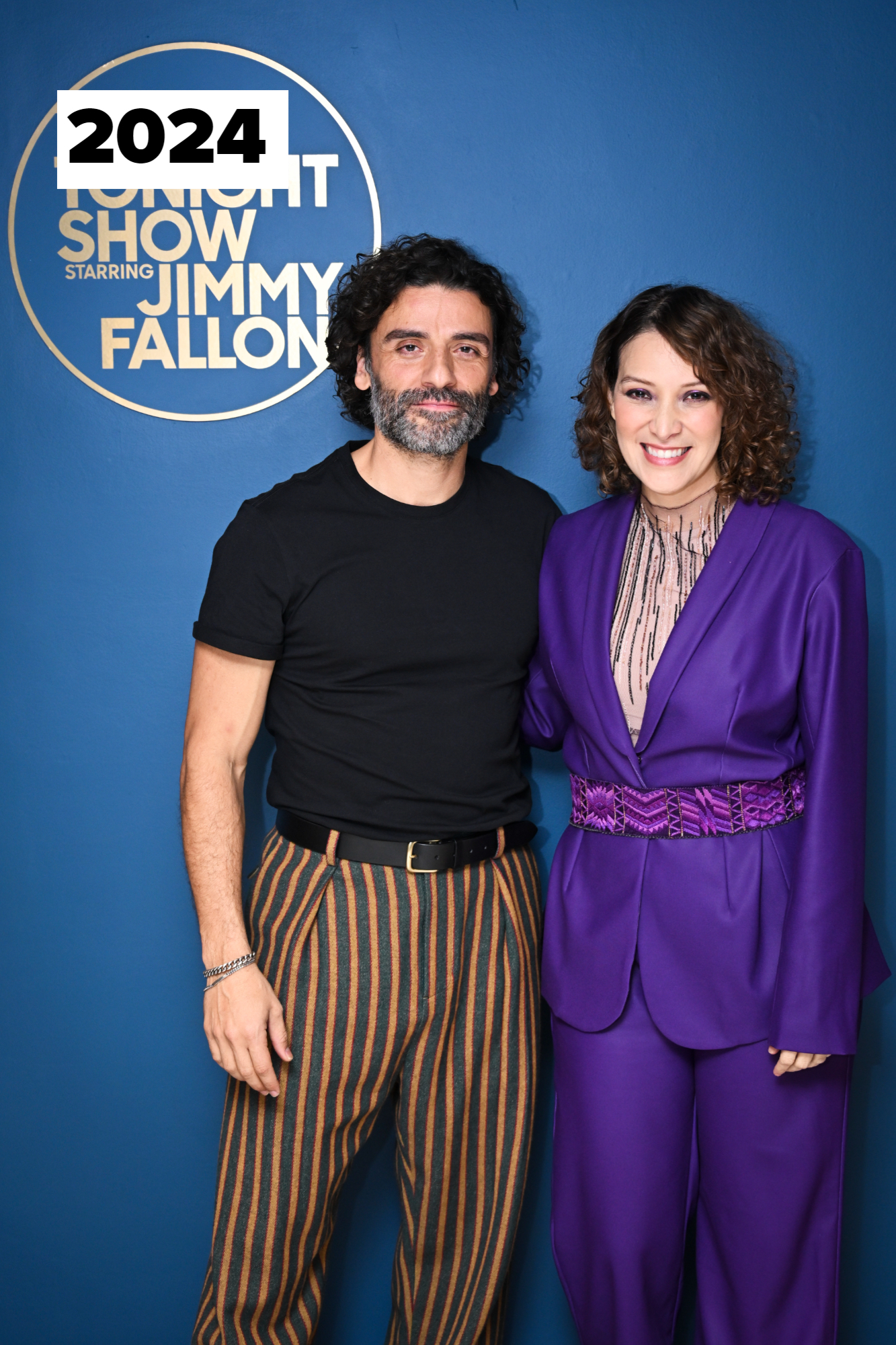 Oscar Isaac in a black shirt and striped pants and Rachel Brosnahan in a purple pantsuit, both smiling, on "The Tonight Show Starring Jimmy Fallon" set