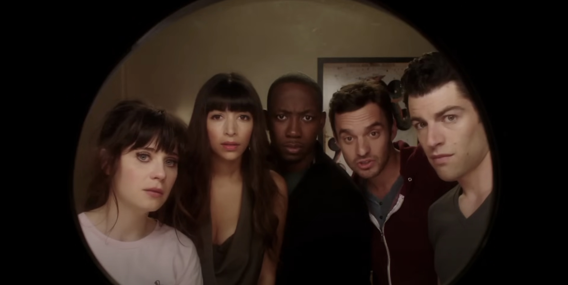 Zooey Deschanel, Hannah Simone, Lamorne Morris, Jake Johnson, and Max Greenfield peer through a peephole in a scene from 'New Girl.'