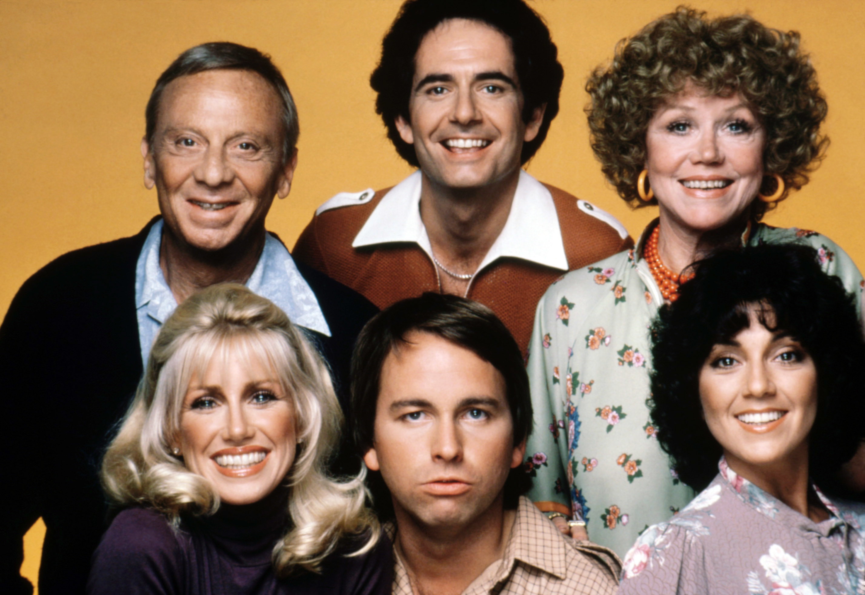 Norman Fell, Suzanne Somers, Richard Kline, Audra Lindley, John Ritter, and Joyce DeWitt posing together against a plain background
