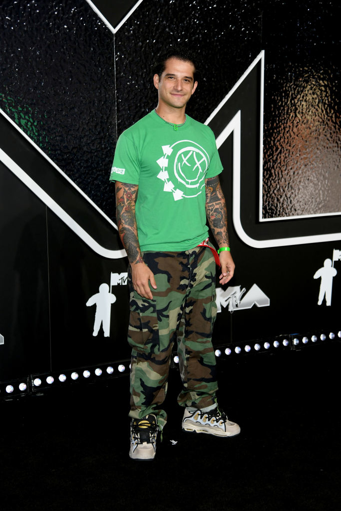 Tyler on the red carpet, wearing a graphic t-shirt and camo pants, in front of an MTV backdrop