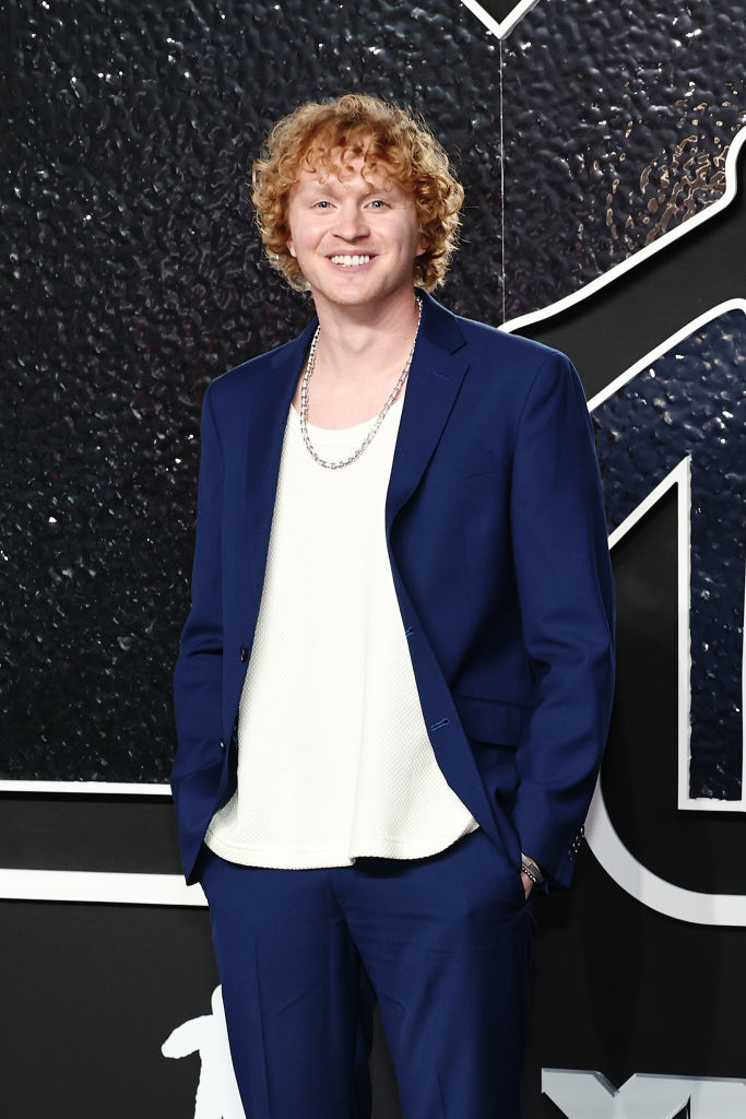 Knox with curly hair in a suit