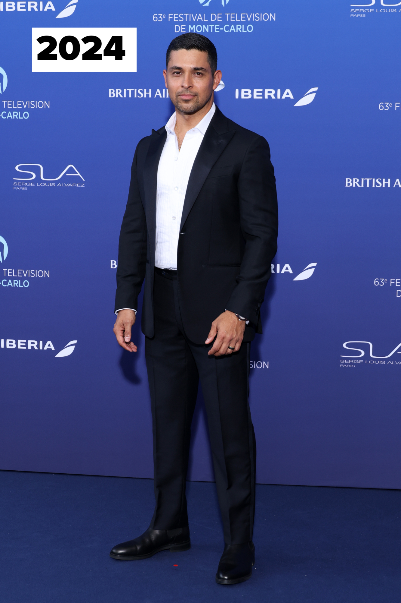 Wilmer Valderrama stands on the red carpet in a black suit and white shirt at the 63rd Festival de Television de Monte-Carlo