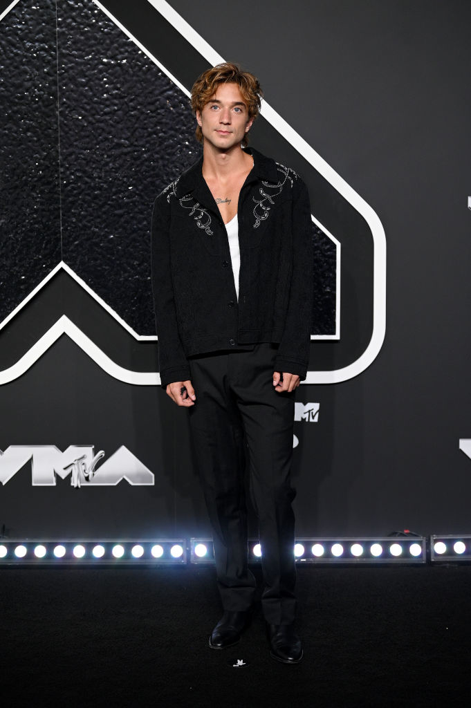 Daniel poses on the carpet wearing embroidered jacket over undershirt