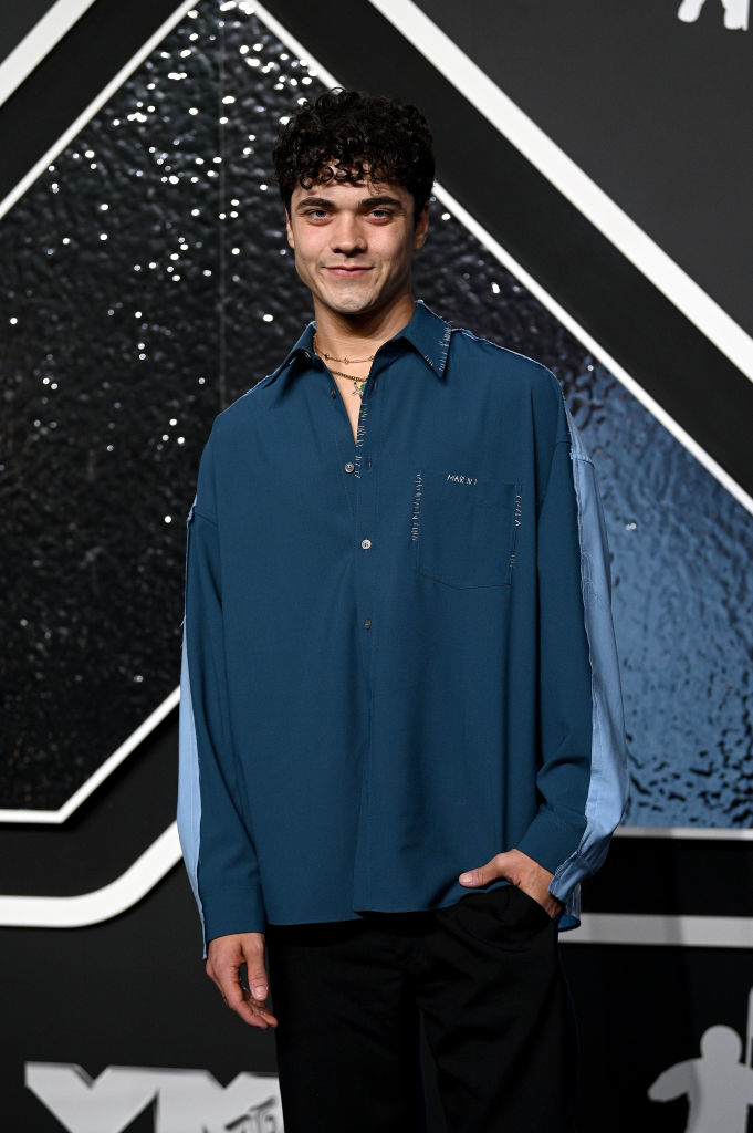Alexander on the red carpet, wearing a relaxed-fit shirt and trousers, smiling at the camera