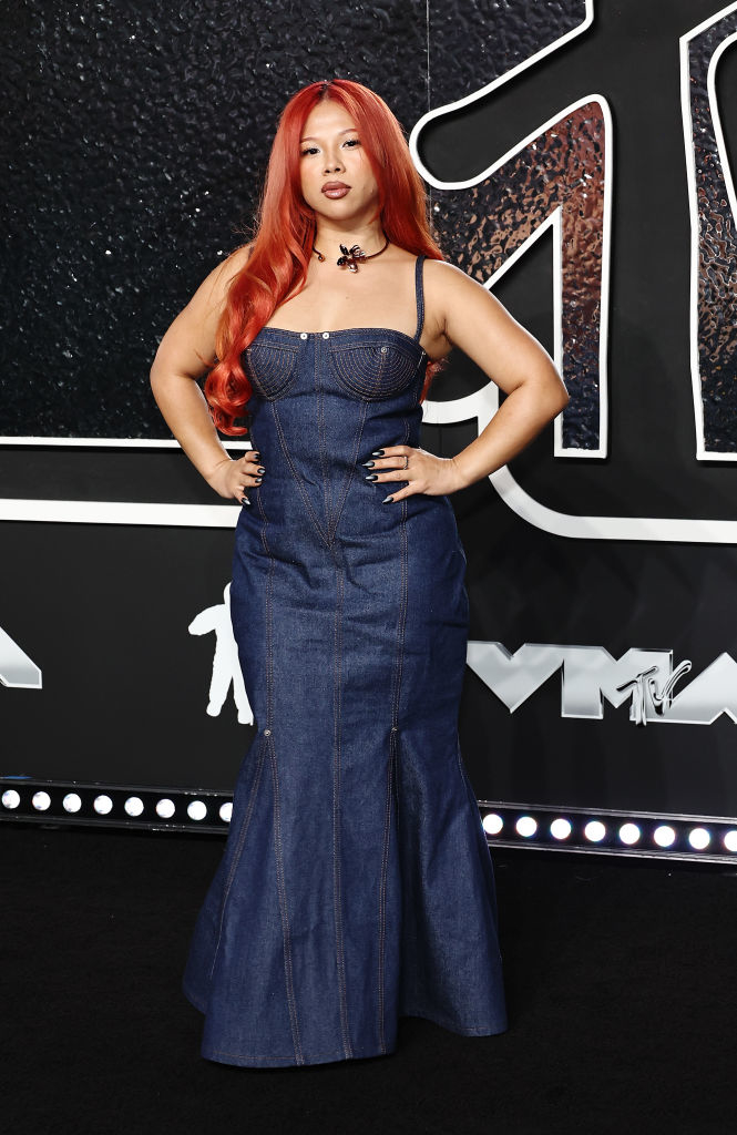 Thủy with long, red hair wears a denim gown on the red carpet at an event