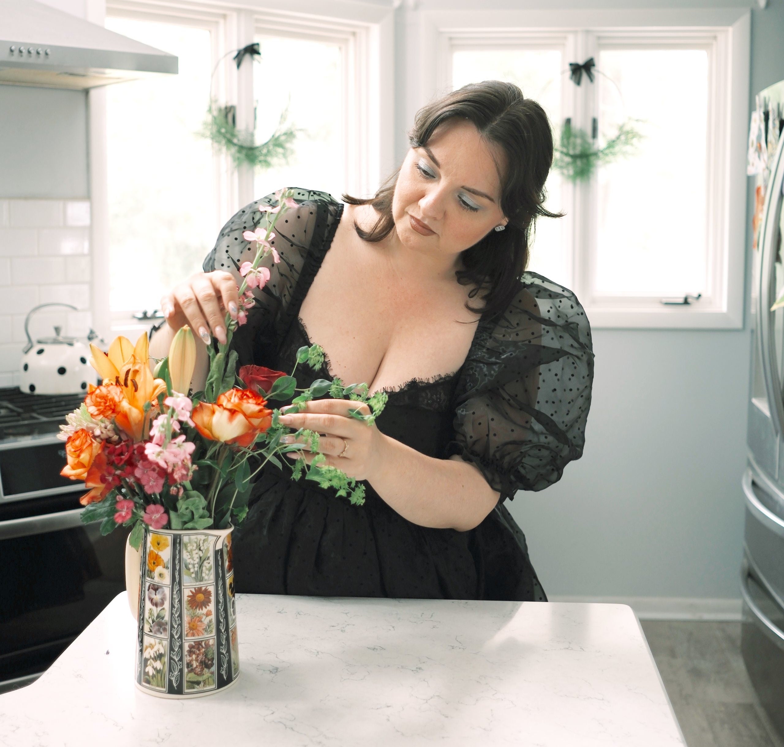 Lynzi in a kitchen arranging flowers in a vase with a floral design