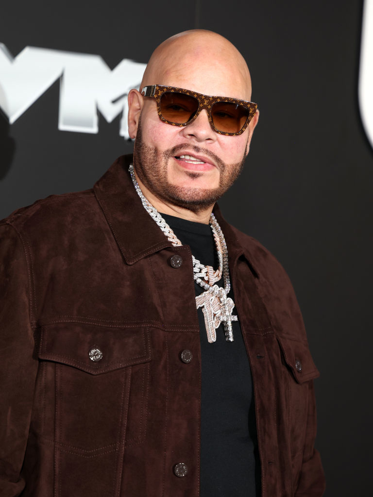 Fat Joe on the red carpet wearing a dark jacket, shirt, sunglasses, and multiple diamond necklaces