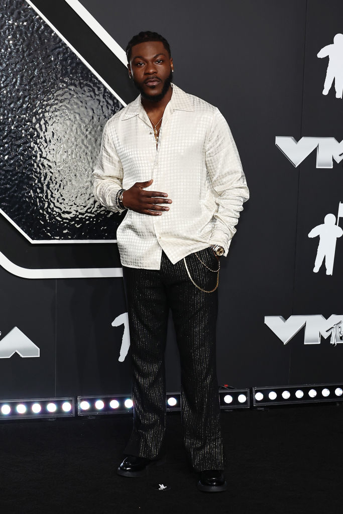 Dometi at the VMAs in a textured shirt and dark pants with a gold chain accessory