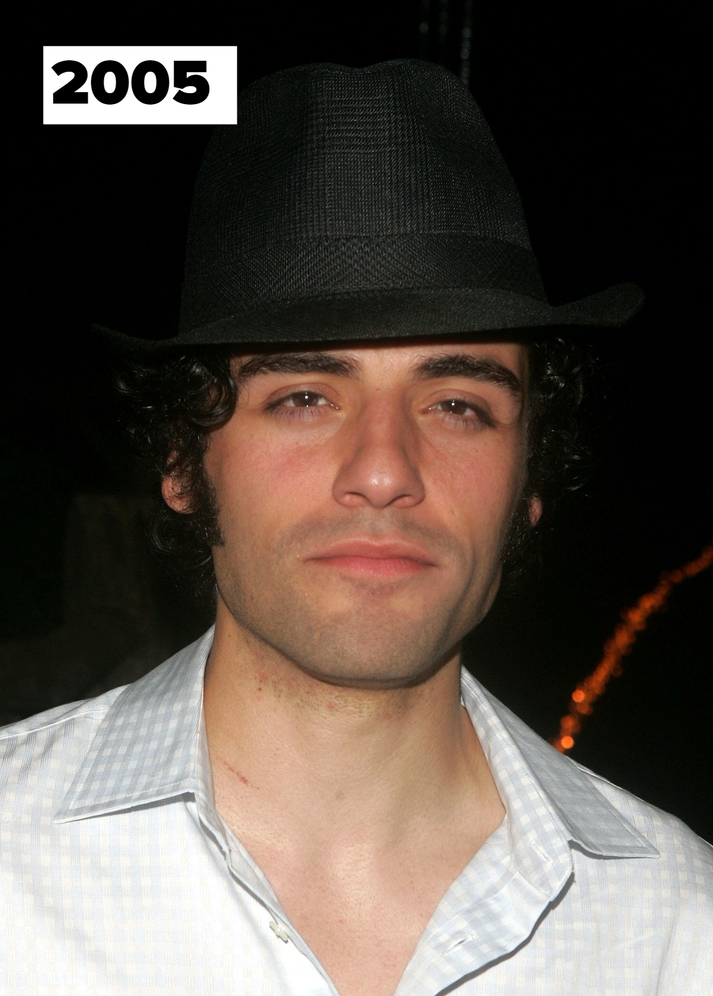 Oscar Isaac with curly hair wearing a hat and a collared shirt