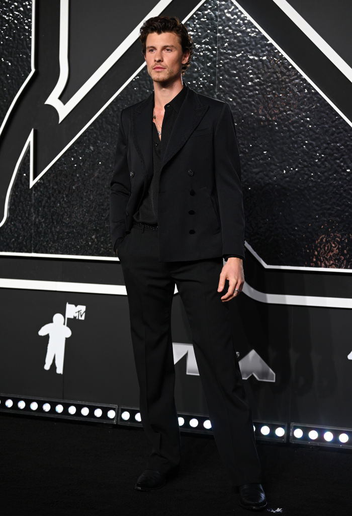 Shawn Mendes on the red carpet, wearing a stylish black double-breasted suit with an open-collared shirt