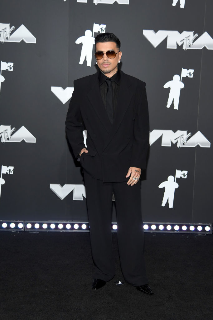 Rauw on the red carpet at the VMAs, wearing a tailored suit with wide-legged pants and sunglasses