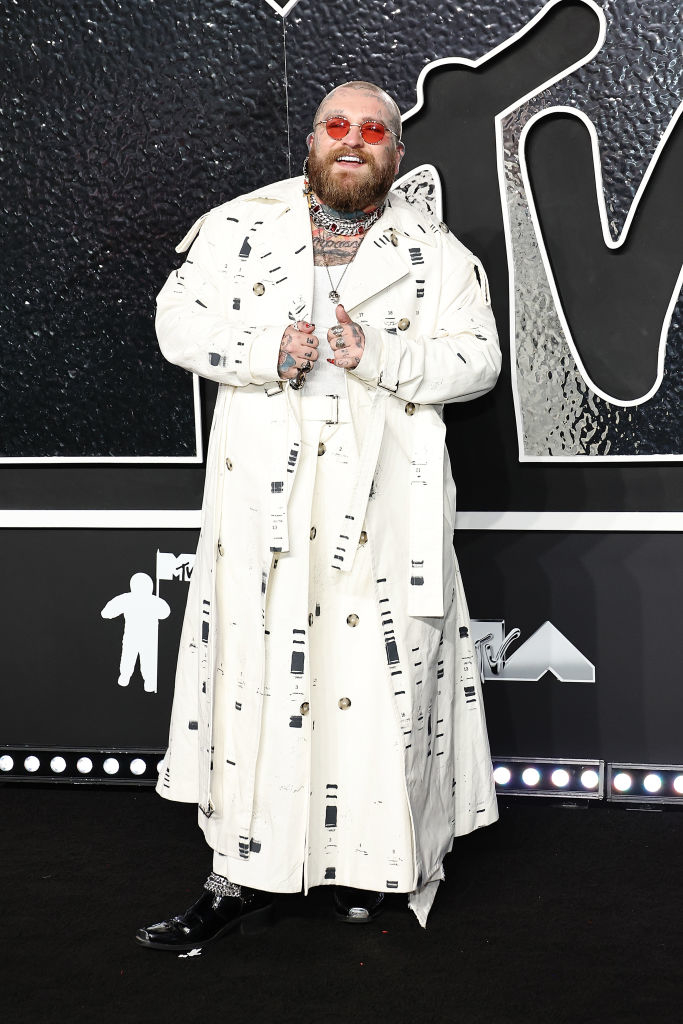 Teddy Swims wearing a patterned, ankle-length coat, pants, and sunglasses