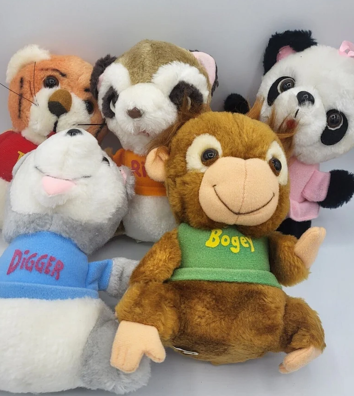 Five plush toys: Digger the gray mole in a blue shirt, Rigger the brown raccoon, Bogey the brown monkey in a green shirt, and a panda and tiger in the back