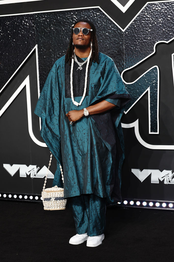 Pheelz at the VMAs in an agbada with sunglasses, beaded necklaces, and a handbag decorated with cowrie shells