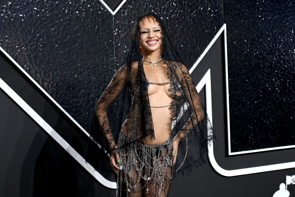 Jazzelle Zanaughtti poses on the red carpet in a revealing outfit featuring chains and lace veils