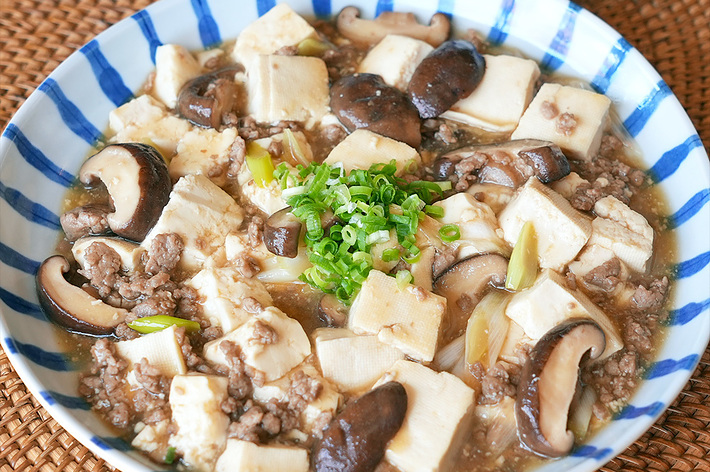 深皿に盛られた麻婆豆腐、挽肉、椎茸、豆腐、ネギが見える。