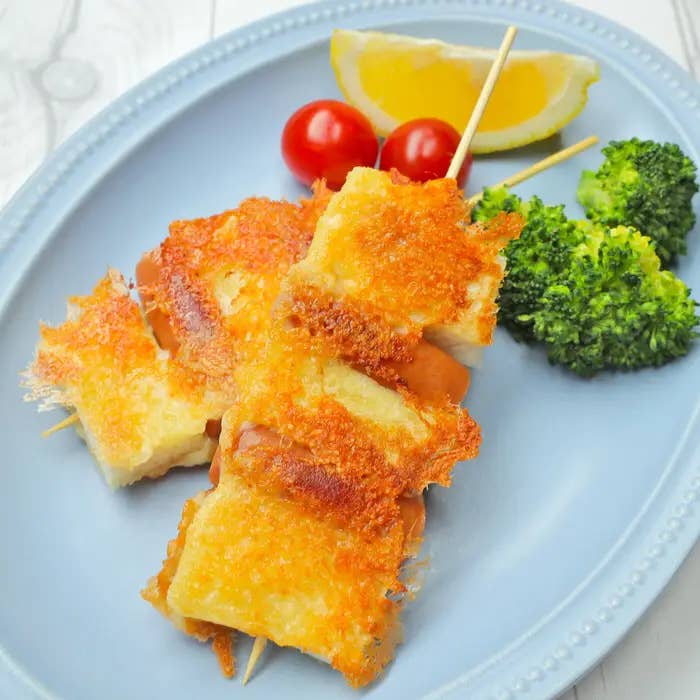 串に刺さった食パンとウインナーが皿にのっており、付け合わせにブロッコリー、ミニトマト、レモンが添えられています。