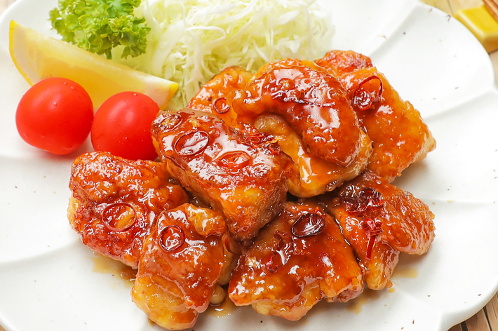 チキンとキャベツの千切り、レタス、ミニトマト、レモンのスライスを彩った白い皿。