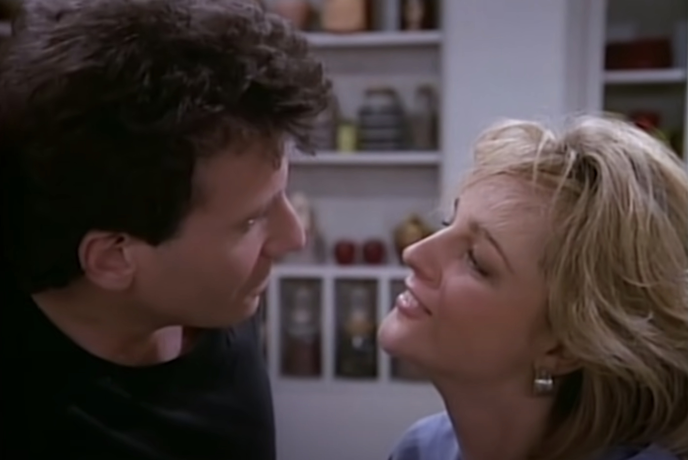 Helen Hunt and Paul Reiser as Jamie and Paul Buchman share a close, affectionate moment in a kitchen scene from the TV show &quot;Mad About You.&quot;