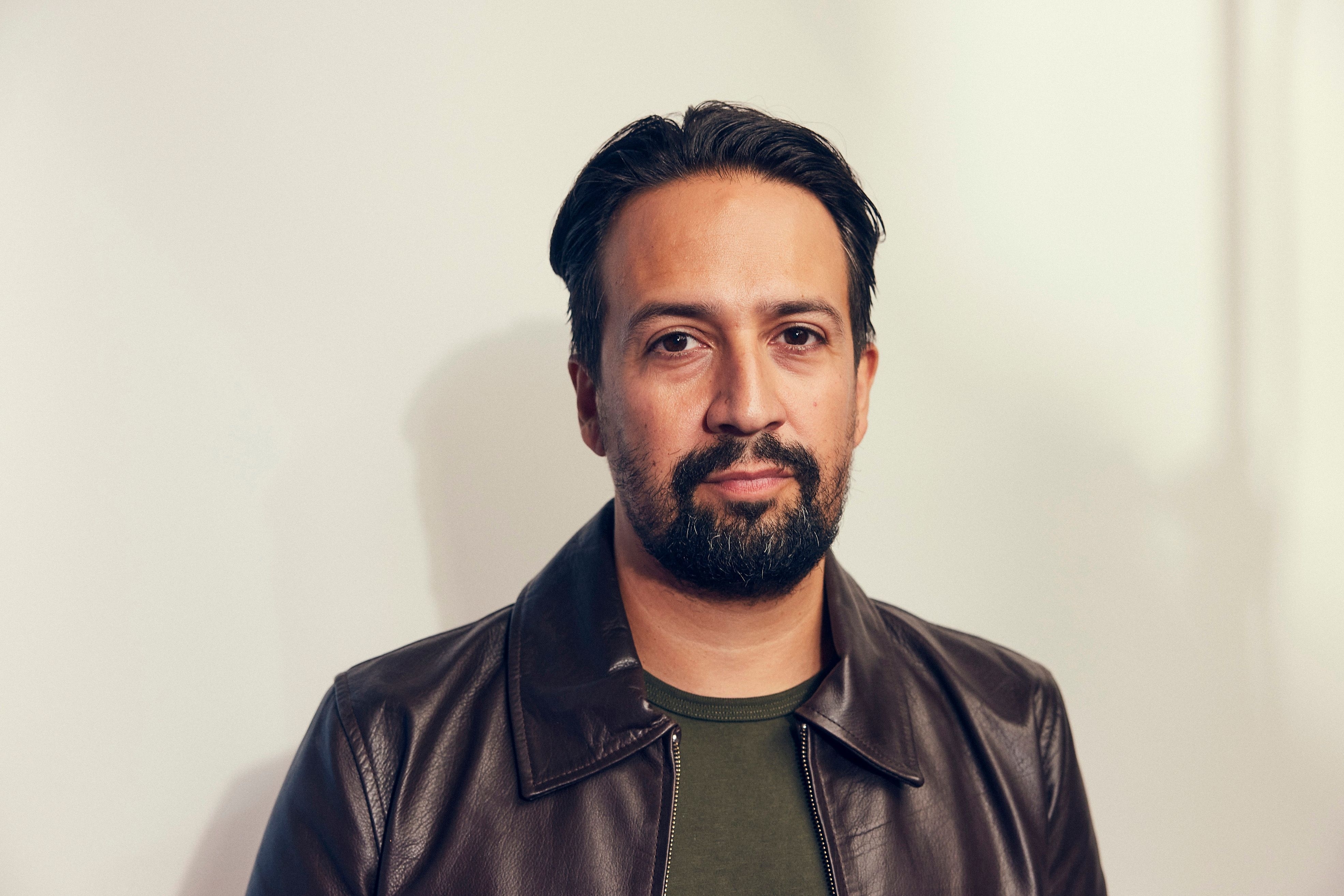 Lin-Manuel Miranda in a casual outfit with a leather jacket, neutral background