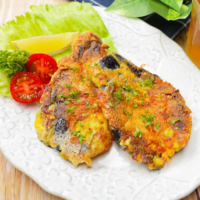 おいしそうな料理プがレタス、レモン、トマトのスライスと共に飾り付けられた白いプレートに盛られています。