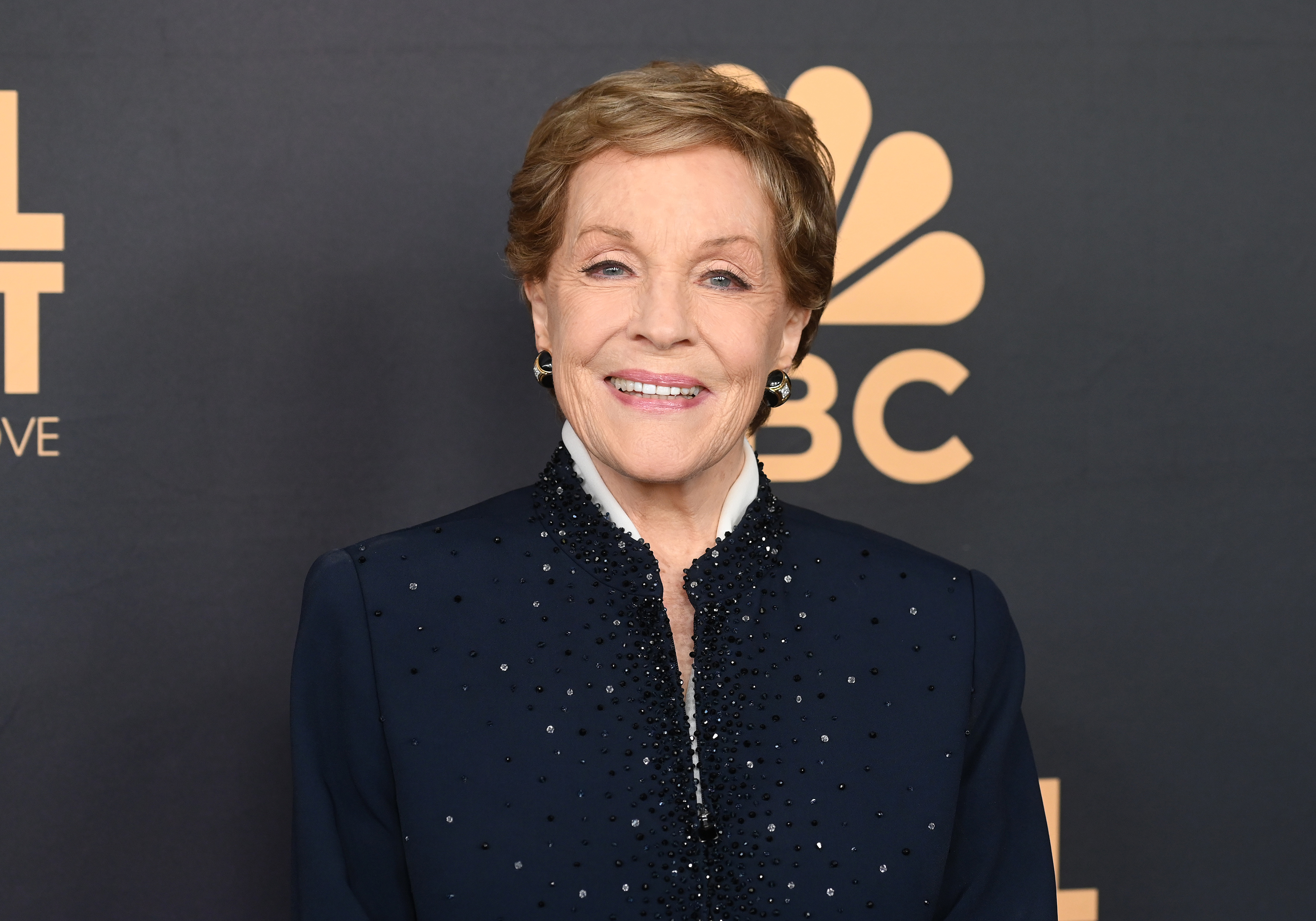 Julie Andrews smiles in an elegant, beaded outfit at a TV event