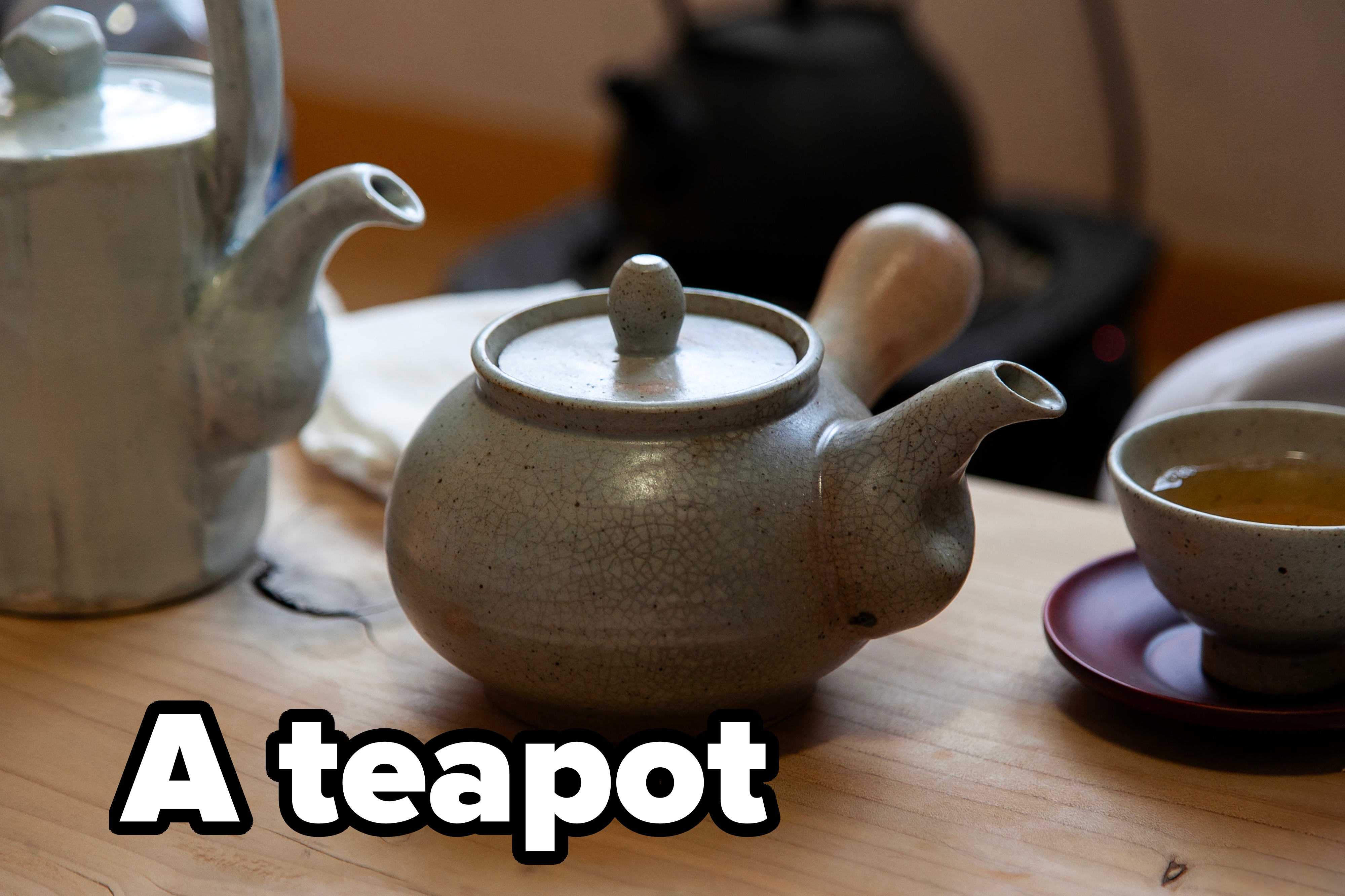 A table with a teapot, a teacup on a saucer, and a ceramic pitcher, set up for tea