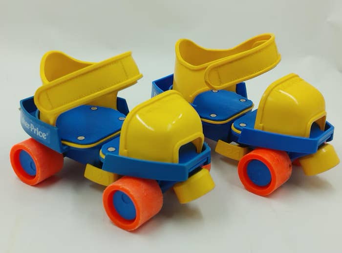A pair of vintage Fisher-Price toddler roller skates with yellow boots, blue bases, and red wheels