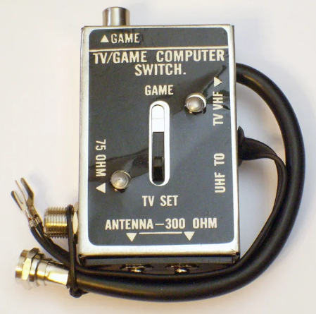 Retro TV/game computer switch box with inputs for TV, game, UHF, VHF, and antenna connections. Features toggle switch and wire leads