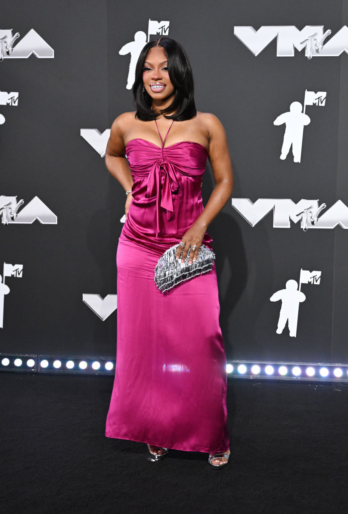 Monaleo on the red carpet at the VMAs wearing a strapless dress with a gathered bust and holding a metallic clutch