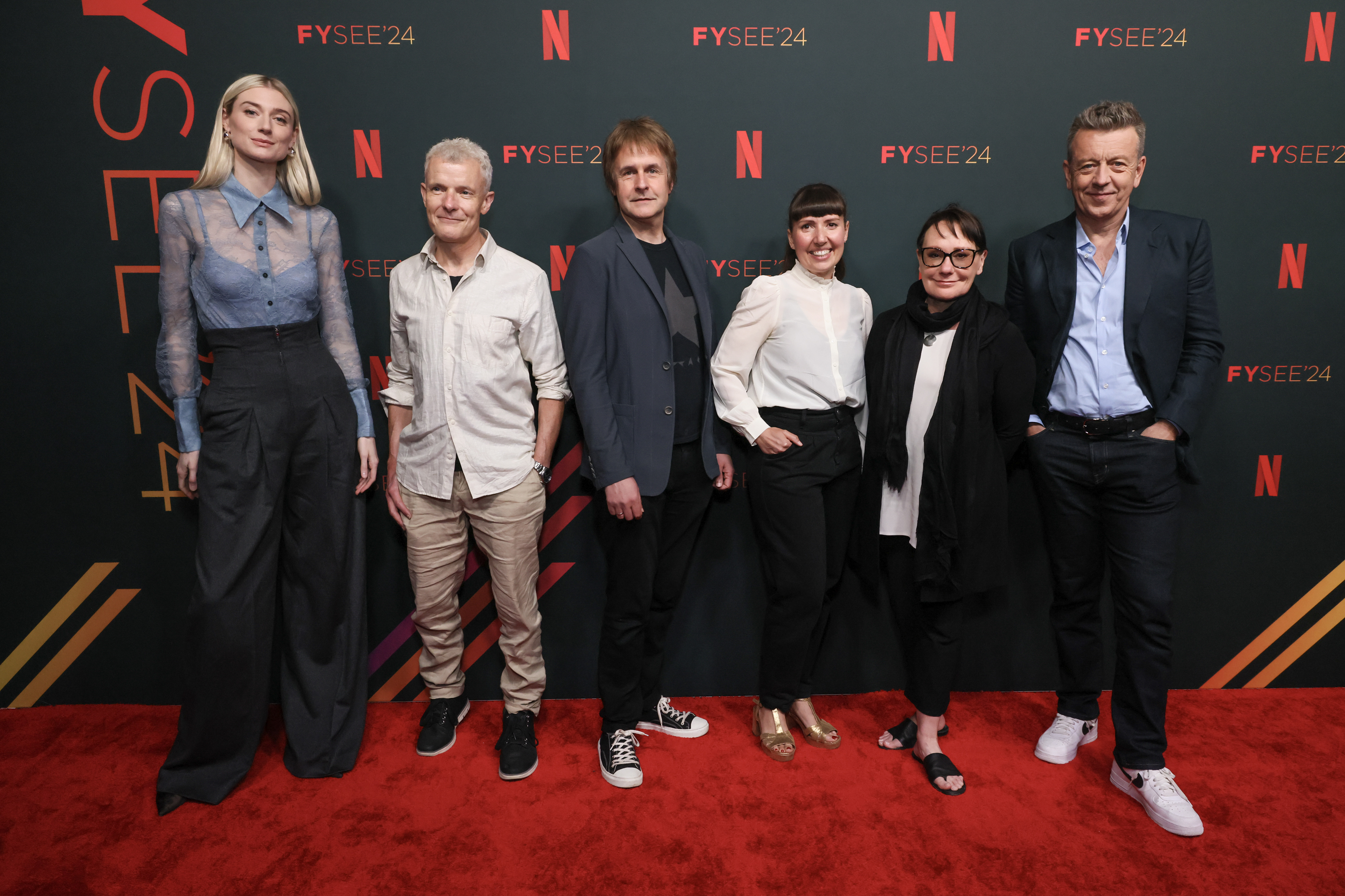 Six people pose on the red carpet at a Netflix event for The Crown