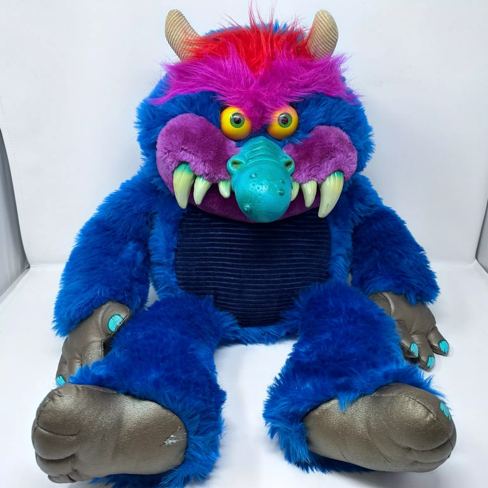 My Pet Monster plush toy with blue fur, a pink nose, large teeth, and orange eyes