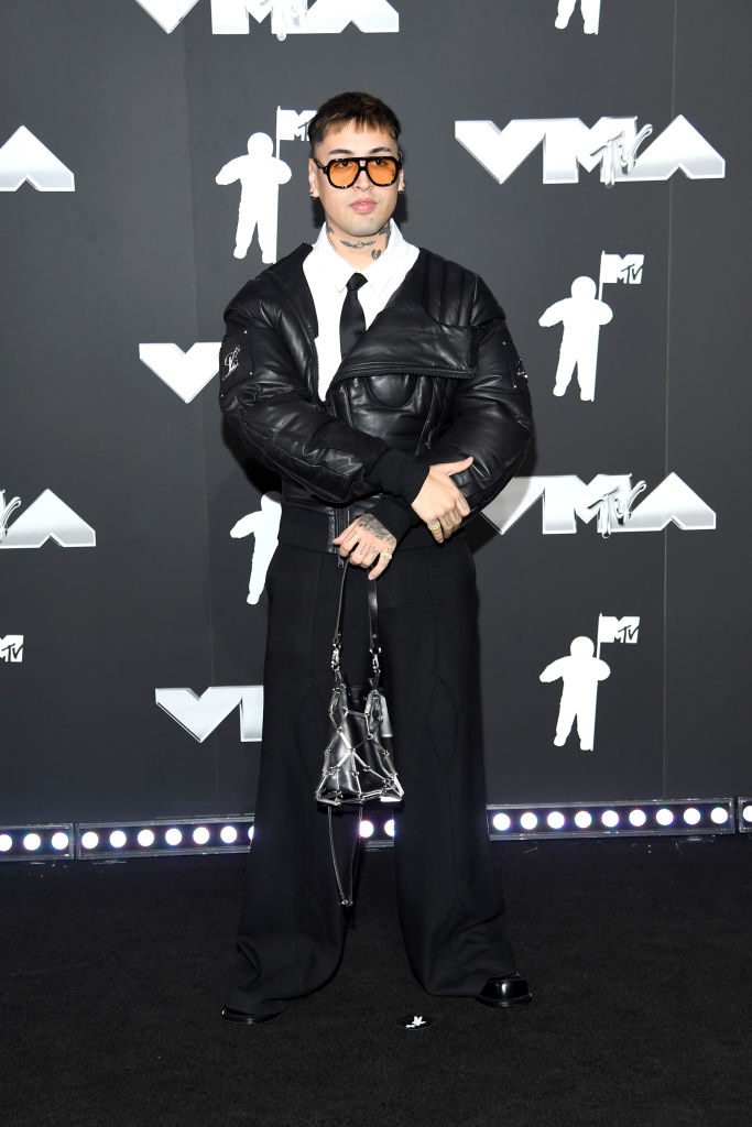 Tiago PZK en la alfombra roja de los MTV Video Music Awards, vistiendo chaqueta acolchada, corbata y pantalones anchos, con gafas de sol y bolso