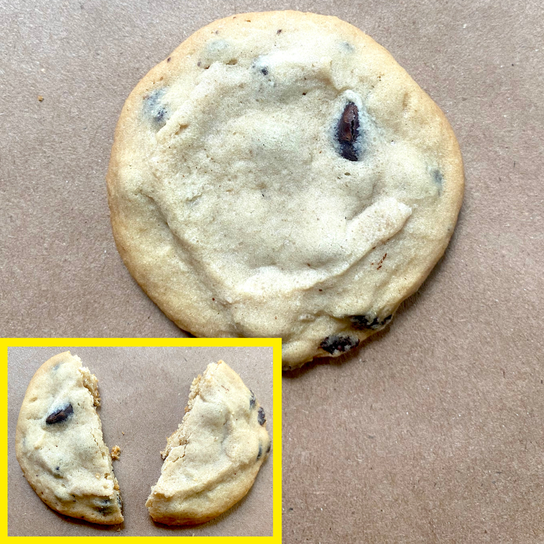 A chocolate chip cookie on a brown surface, with an inset showing the cookie broken in half