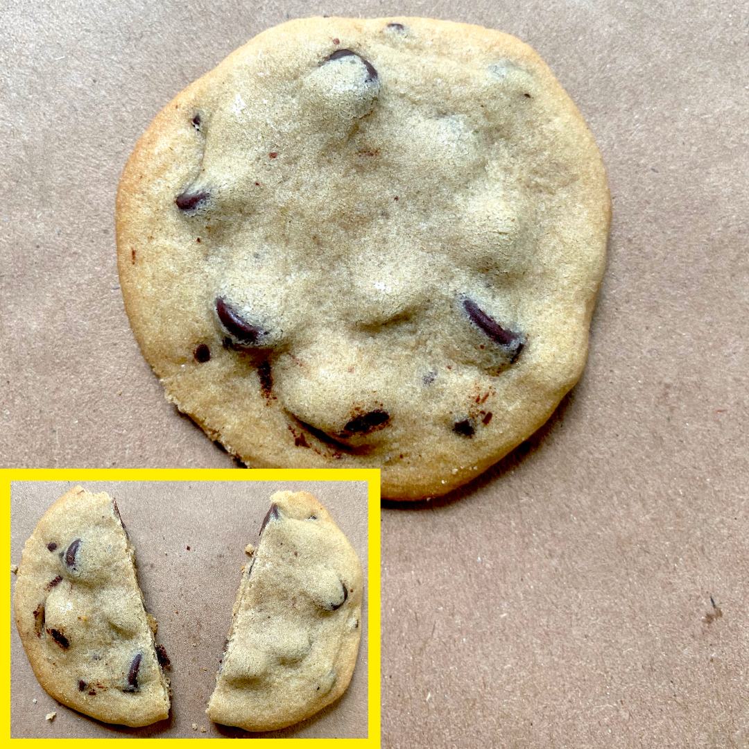 A chocolate chip cookie on a brown surface with an inset image showing the same cookie broken in half
