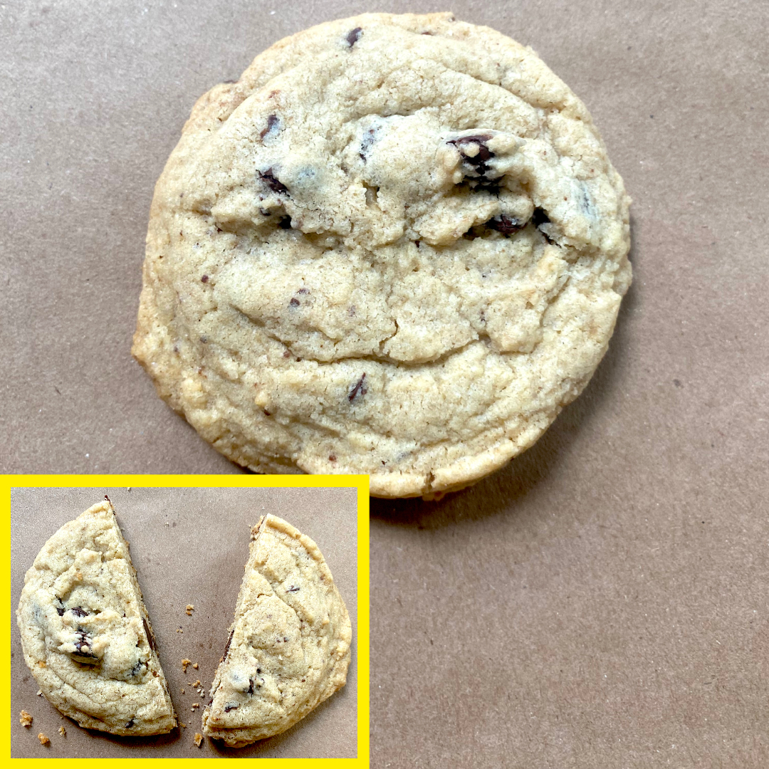 A single chocolate chip cookie is shown on a surface. An inset image shows the same cookie halved, revealing chocolate chips inside
