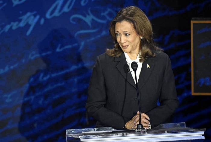 Kamala Harris stands behind a podium, looking slightly to her right with hands folded, during the debate