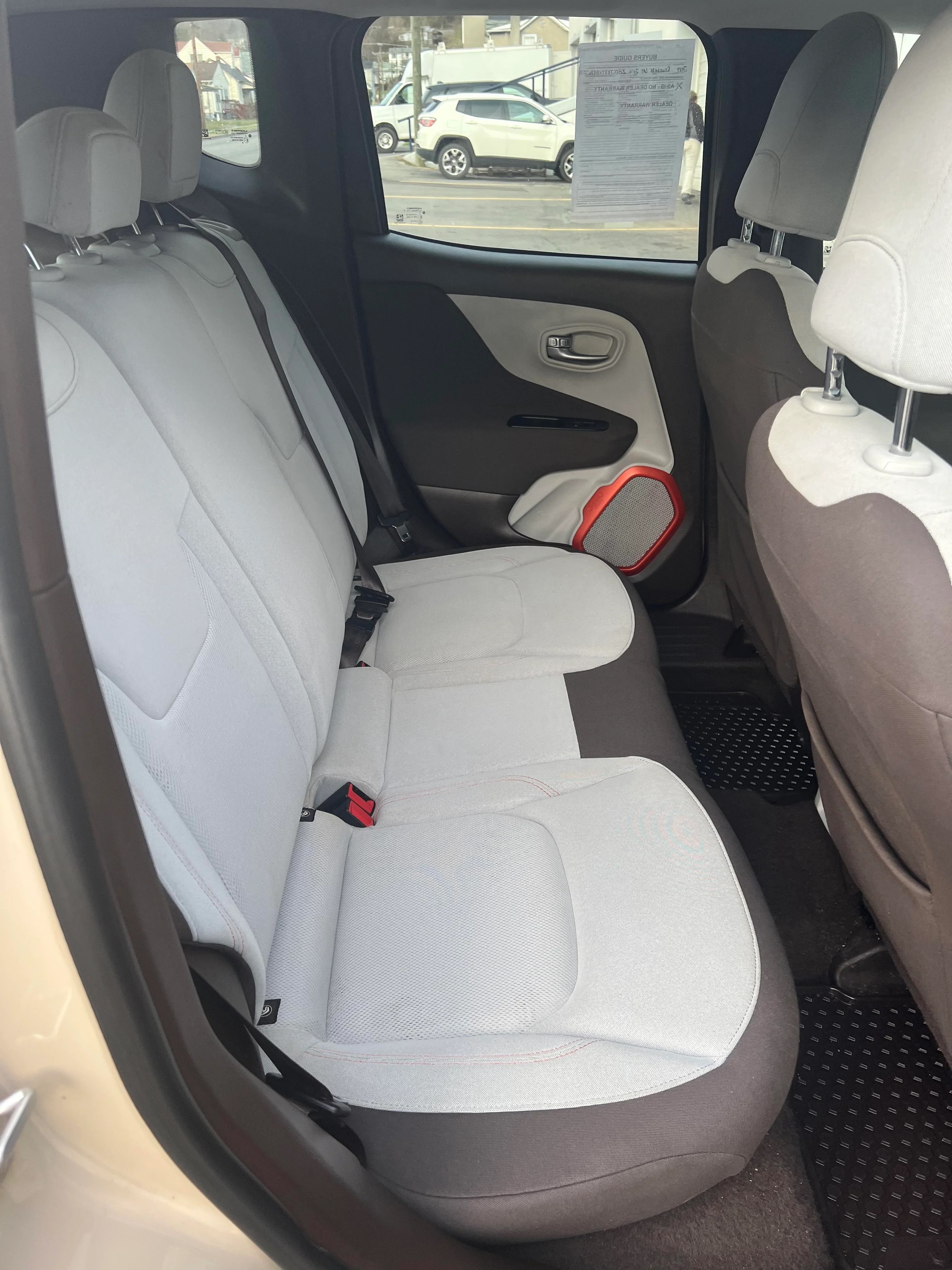 Car interior showing the back seats and part of the front seats. The car's rear doors are open, displaying the seating arrangement and part of the door panel
