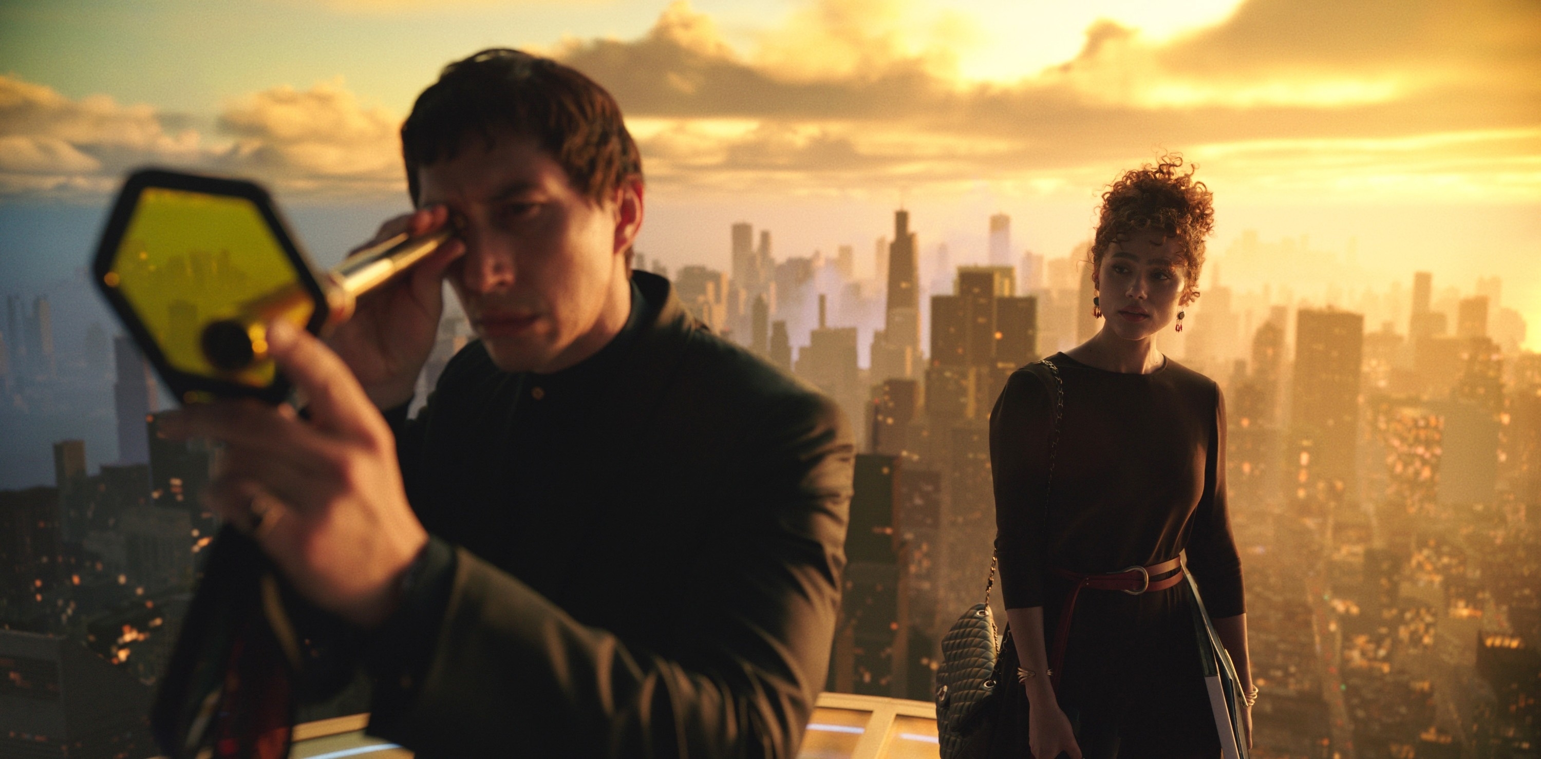 Two people are shown, with one holding a device to their eye. A cityscape is visible in the background, suggesting a scene from a movie or TV show