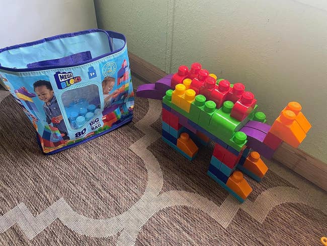 Mega Bloks large  container  with 80 pieces shown adjacent  to a colorful dinosaur operation   built with the blocks