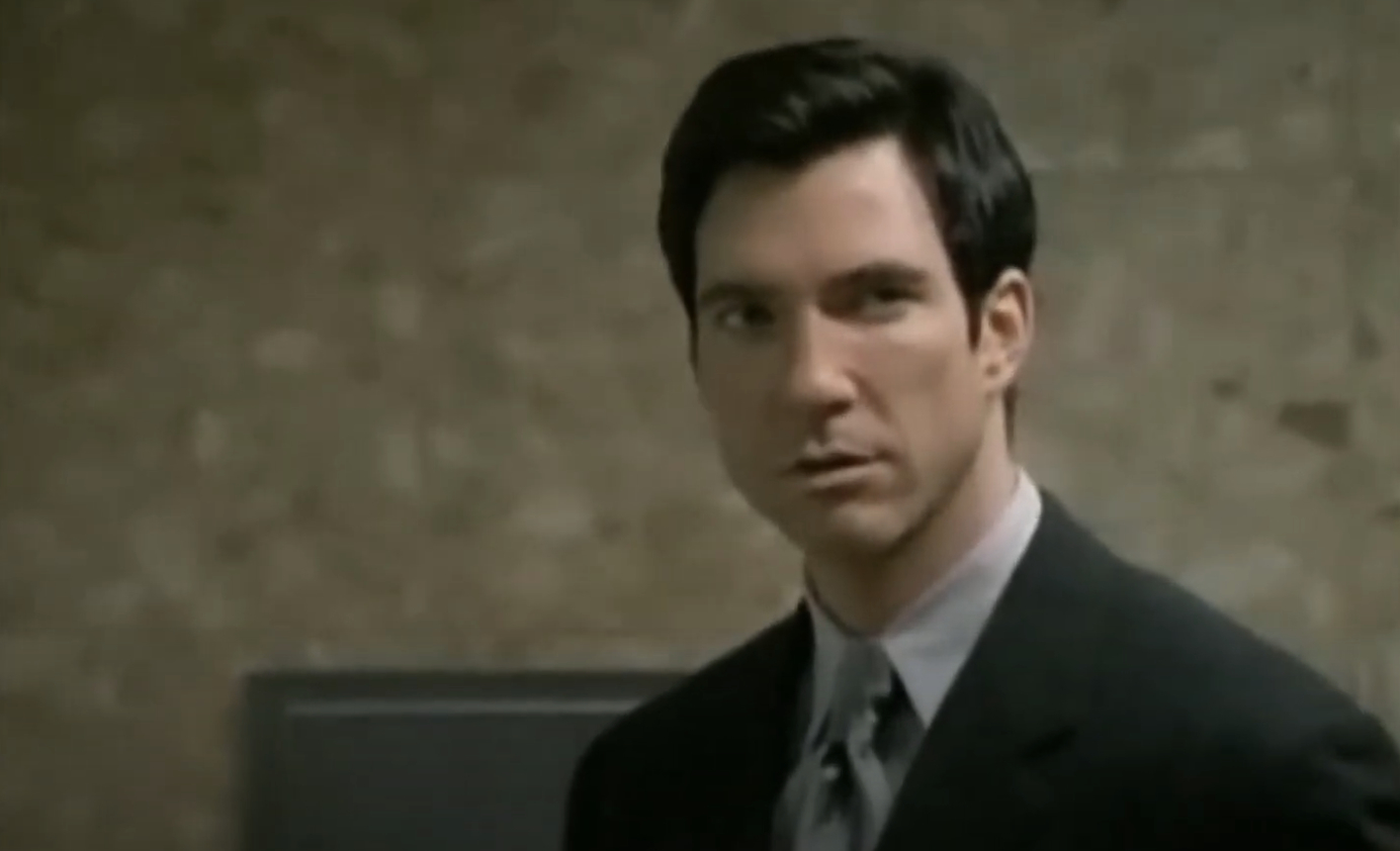 Dylan McDermott wearing a suit and looking serious in a scene from a TV or movie