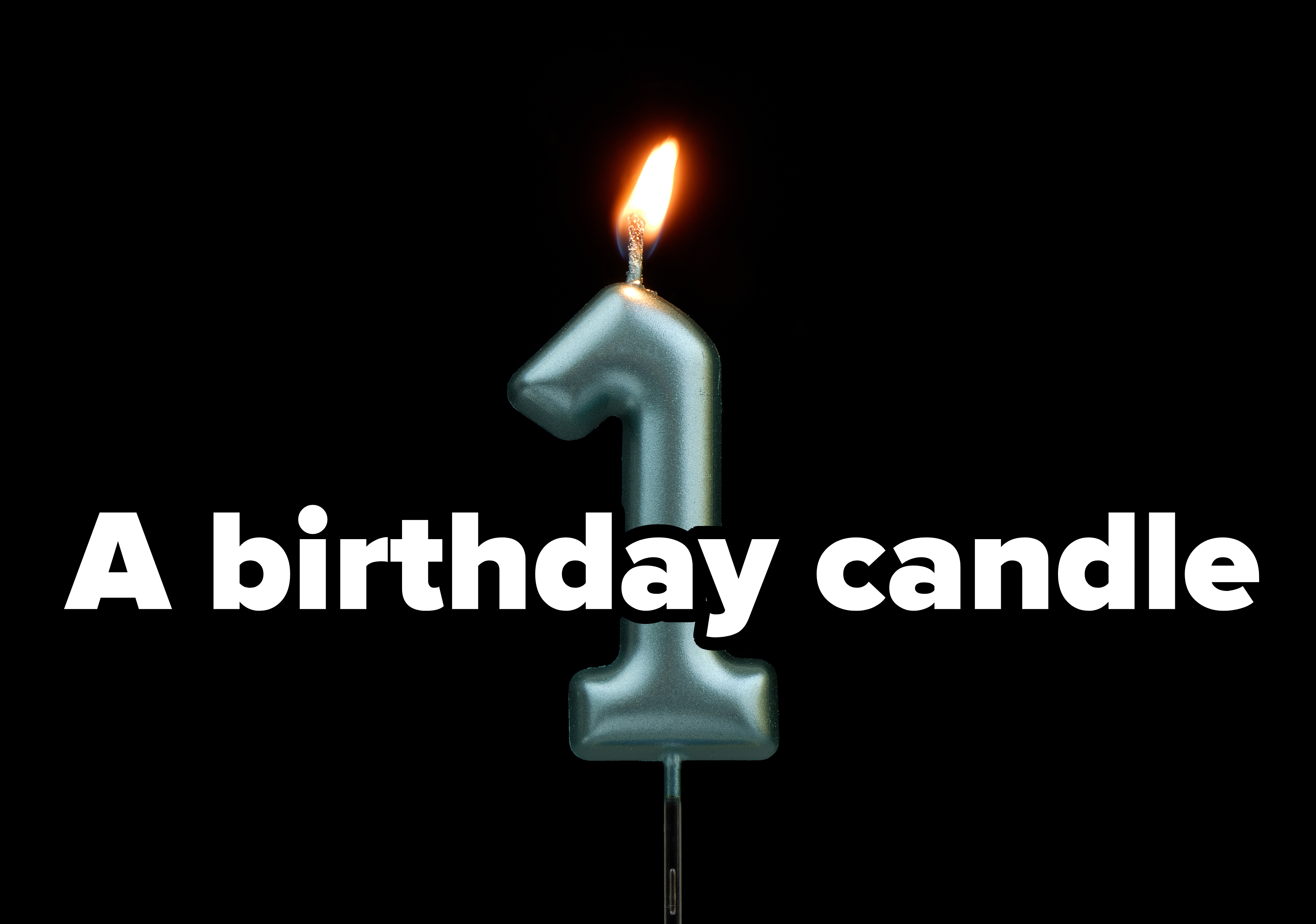 A lit birthday candle in the shape of the number one against a black background